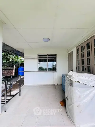 Spacious outdoor balcony with tiled flooring and partial garden view, perfect for relaxation.