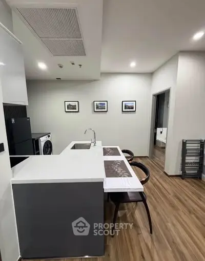 Modern kitchen with sleek design and wooden flooring in a contemporary apartment.