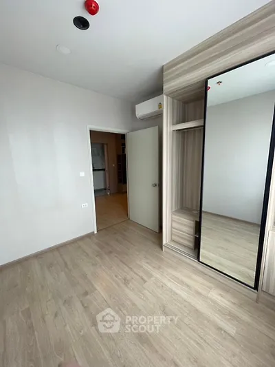 Spacious modern bedroom with wooden flooring and mirrored wardrobe