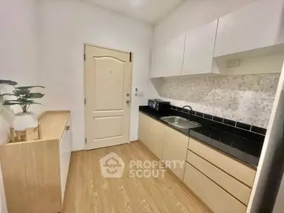 Modern kitchen with sleek cabinetry and stylish backsplash in a cozy apartment.