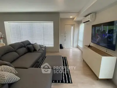 Modern living room with sleek gray sofa and large TV, perfect for relaxation.