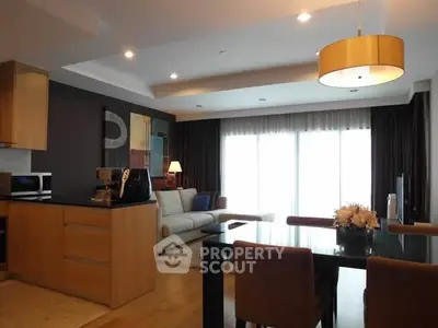 Modern open-plan living room with stylish kitchen and dining area, featuring elegant lighting and contemporary decor.