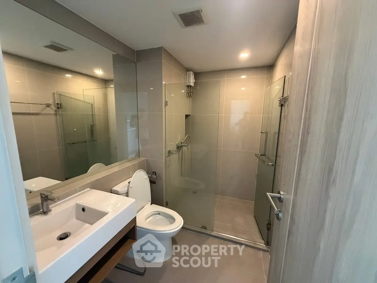 Modern bathroom with sleek design, glass shower, and elegant fixtures in a contemporary apartment.