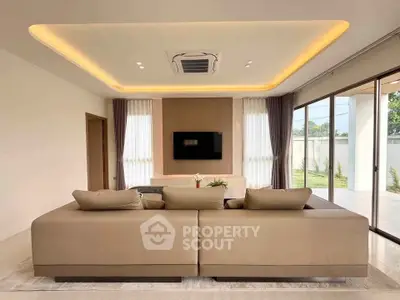 Luxurious modern living room with elegant ceiling lights and large windows offering garden views.