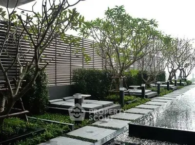 Luxurious outdoor garden with modern lounge chairs and water feature in a serene setting.