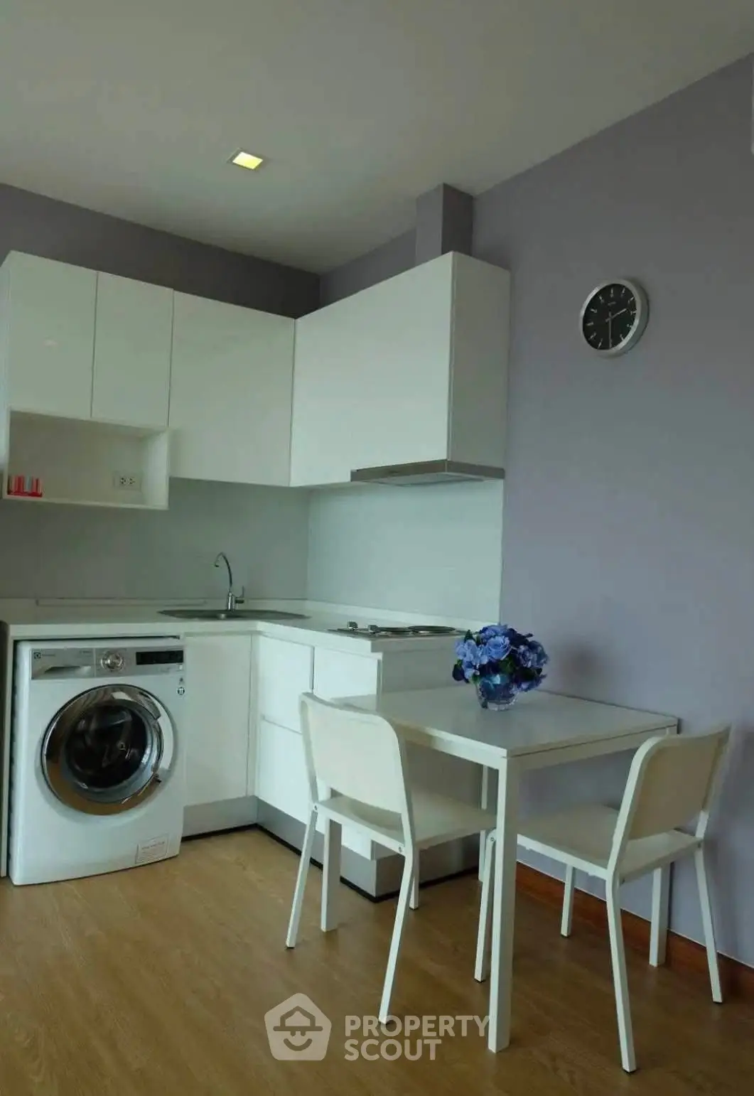 Modern kitchen with white cabinets, washing machine, and dining area in a stylish apartment.