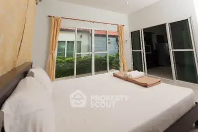 Spacious bedroom with large windows and garden view, featuring modern decor and cozy ambiance.