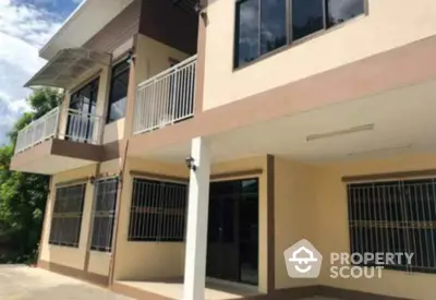 Modern two-story house with large windows and balcony in a serene neighborhood.