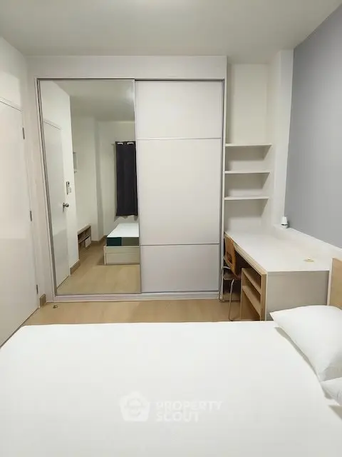 Modern bedroom with mirrored closet and study desk, perfect for urban living.