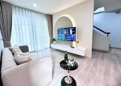 Modern living room with stylish decor and wall-mounted TV, featuring elegant curtains and cozy seating.