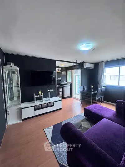 Modern living room with stylish decor and open layout, featuring a cozy purple sofa and dining area.