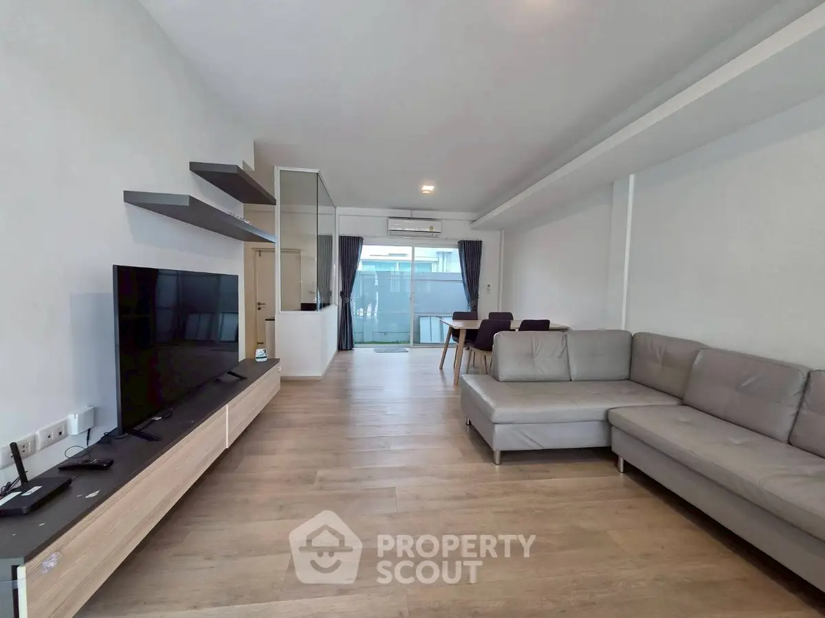 Spacious modern living room with sleek furniture and large TV, perfect for relaxation.