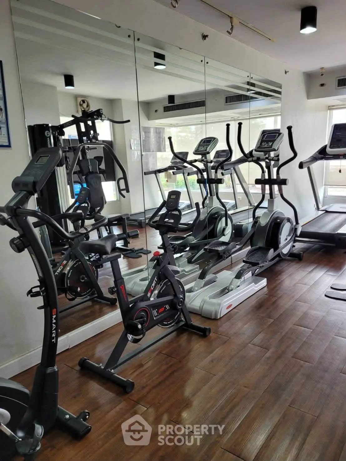 Modern gym with state-of-the-art exercise equipment and mirrored walls in a residential building.