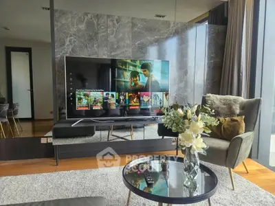 Modern living room with stylish decor and large TV, featuring elegant furniture and natural light.