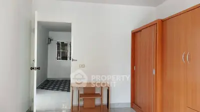 Spacious bedroom with wooden wardrobe and open door to hallway