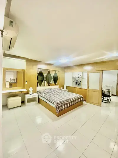 Spacious bedroom with modern decor and ample natural light, featuring a comfortable bed and stylish furnishings.