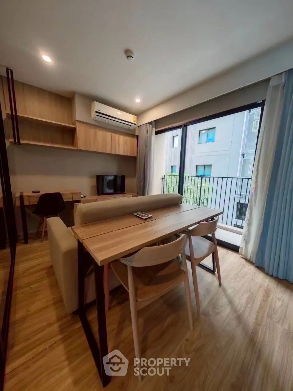 Modern living room with balcony view, stylish furniture, and natural light in urban apartment.