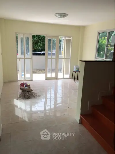 Spacious living room with large windows and garden view, perfect for natural light lovers.