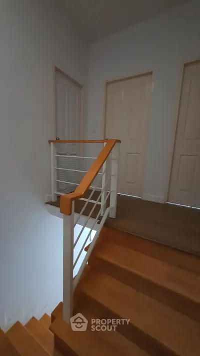 Modern staircase with wooden steps and sleek railing in a contemporary home interior.
