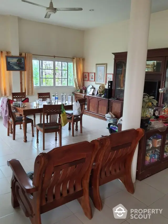 Spacious and inviting living area with elegant wooden furniture, large windows, and a cozy dining space, perfect for family gatherings.