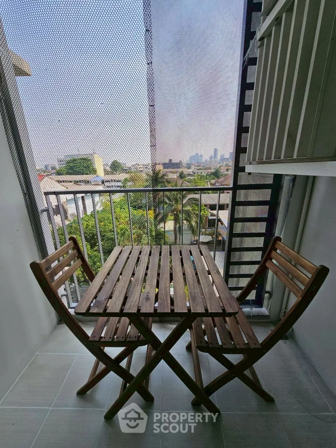 Charming balcony with wooden furniture and city view, perfect for relaxation.