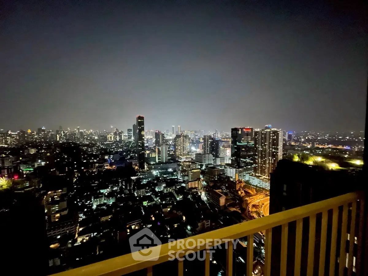 Stunning cityscape view from high-rise balcony at night, showcasing vibrant urban lights.