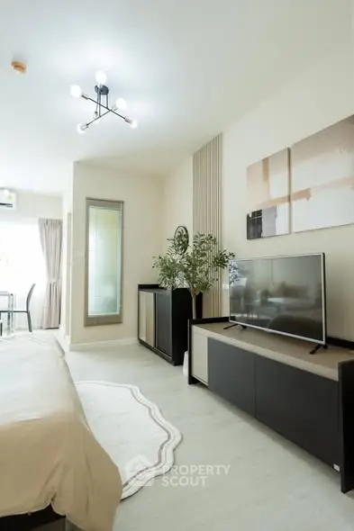Modern living room with stylish decor and large TV unit in a bright apartment.