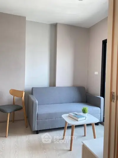 Modern living room with stylish gray sofa and wooden chairs, perfect for cozy relaxation.