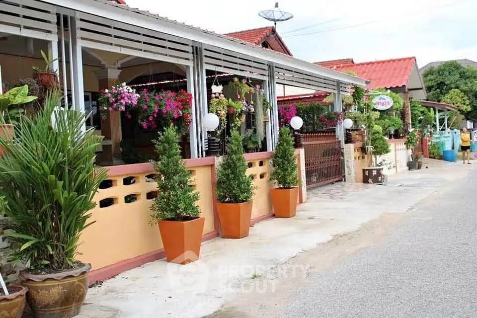Charming suburban house with vibrant garden and potted plants lining the entrance, perfect for family living.