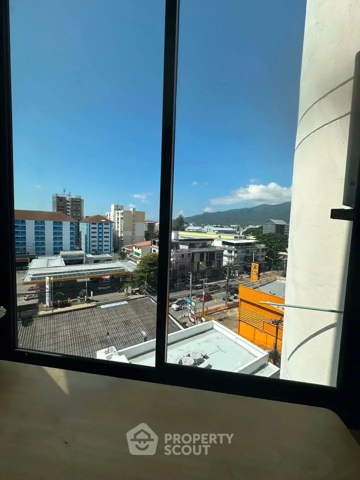 Stunning cityscape view from a high-rise window, showcasing urban living with mountain backdrop.
