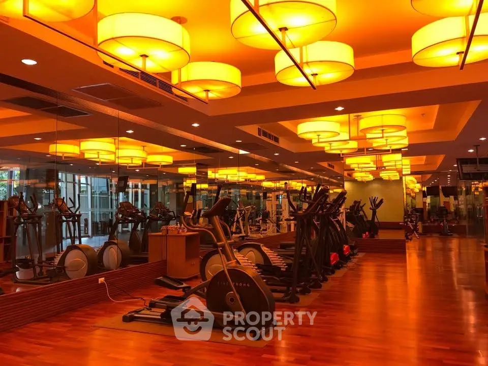 Luxurious gym with modern equipment and ambient lighting in upscale residential complex.