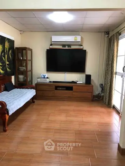 Spacious living room with modern TV setup and elegant wooden furniture.