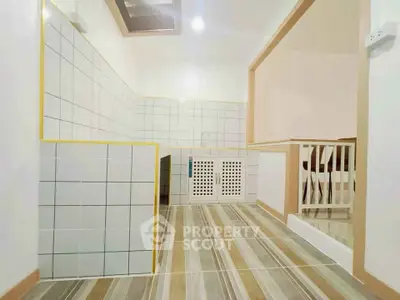 Modern kitchen with tiled walls and wooden flooring, featuring an open layout design.