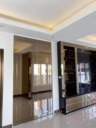 Modern living room with sleek mirrored cabinets and elegant ceiling lighting.