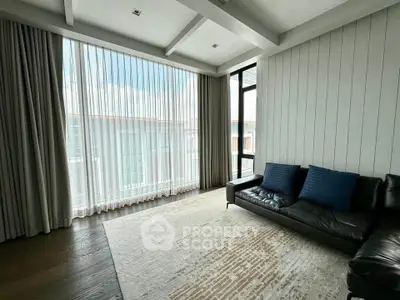 Spacious living room with large windows and modern decor, perfect for natural light lovers.