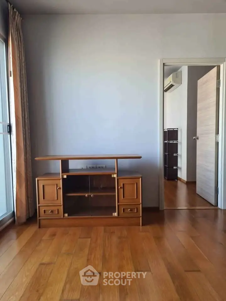 Spacious living room with wooden flooring and elegant TV stand, perfect for modern living.