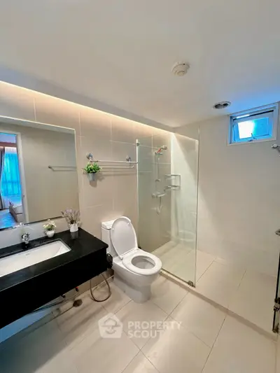 Modern bathroom with glass shower and sleek fixtures in contemporary apartment.