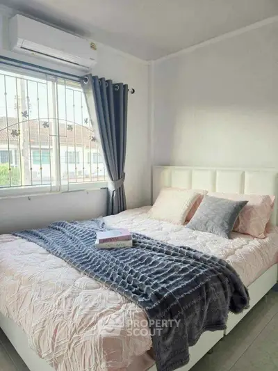 Cozy bedroom with stylish decor and large window offering natural light.