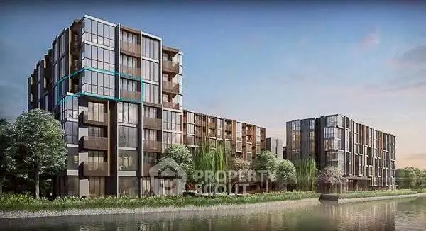 Modern riverside apartment buildings with glass facades and lush greenery.
