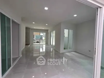 Spacious modern living room with large windows and glossy tiled floors in a contemporary home.