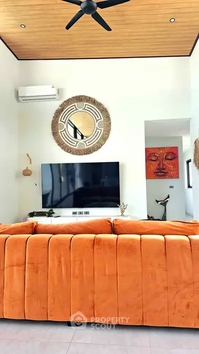 Stylish living room with vibrant orange sofa, modern decor, and wall-mounted TV, perfect for contemporary living.