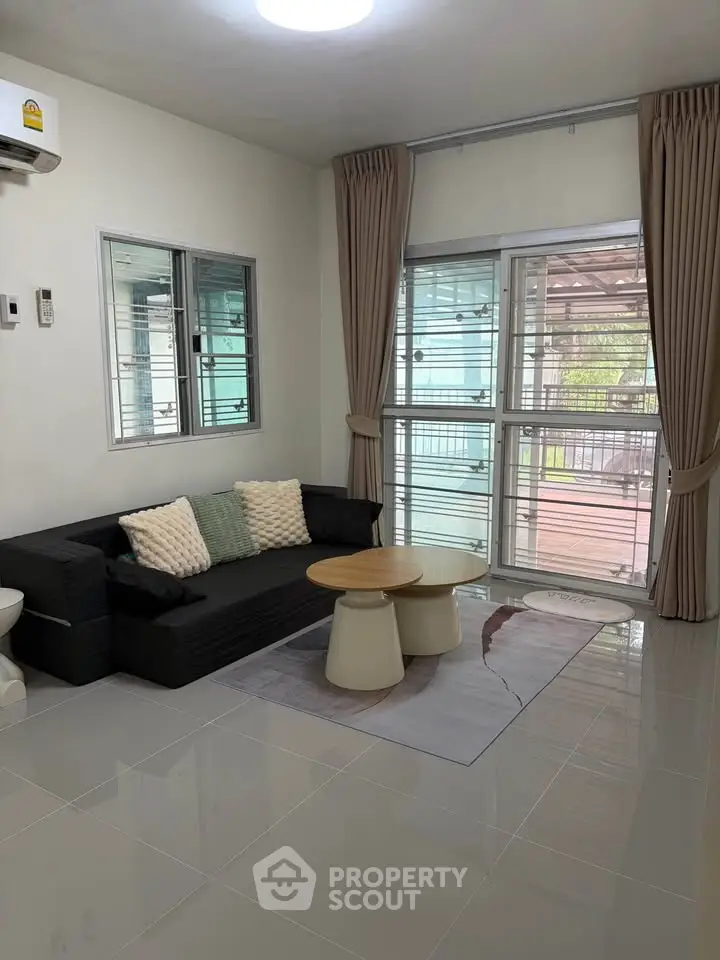 Modern living room with sleek black sofa, stylish coffee table, and large windows offering natural light.