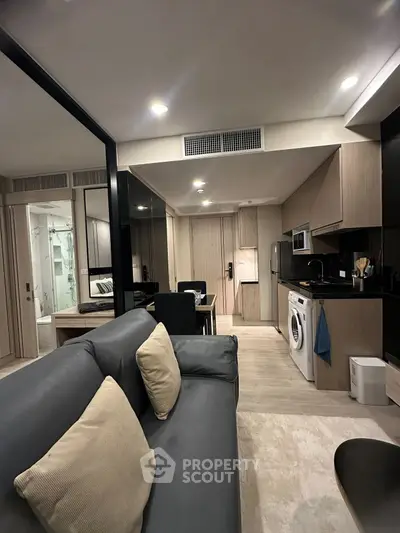 Modern apartment interior with sleek kitchen and cozy living area, featuring built-in appliances and stylish decor.