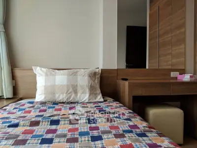 Cozy bedroom with colorful quilt and wooden furniture, perfect for relaxation.