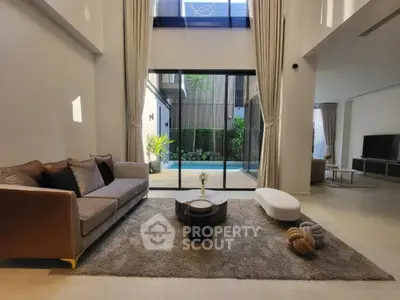 Luxurious living room with pool view, modern furniture, and high ceilings in a contemporary home.