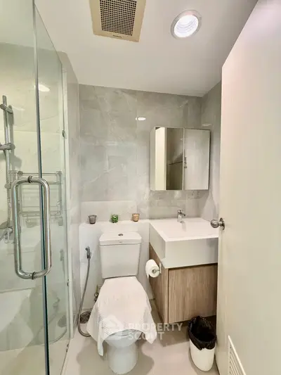 Modern bathroom with glass shower and sleek vanity in contemporary apartment.