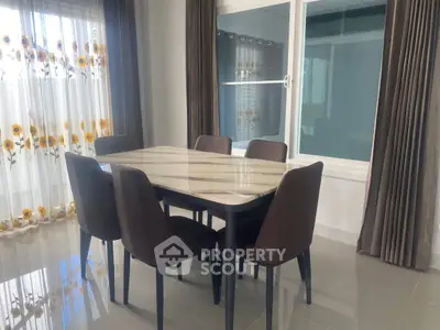 Elegant dining area with modern table and chairs, sunlit by floral curtains, perfect for family gatherings.