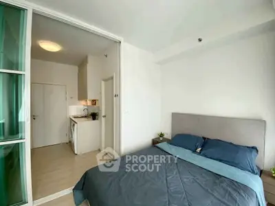 Modern bedroom with sliding glass door leading to compact kitchen area.