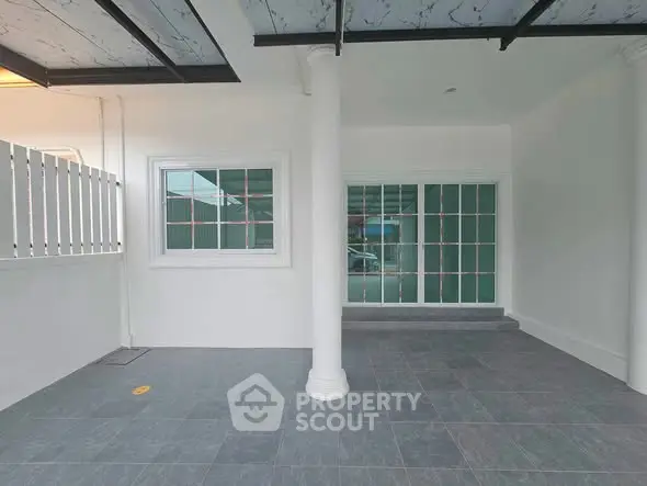 Spacious covered parking area with tiled flooring and large windows.