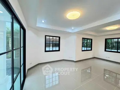 Spacious modern living room with large windows and elegant ceiling lights.